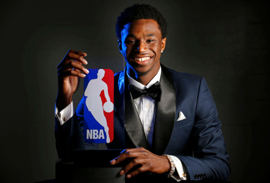 Andrew Wiggins smiling in sharp suit holding 2015 NBA Rookie of the Year trophy dark background Wallpaper
