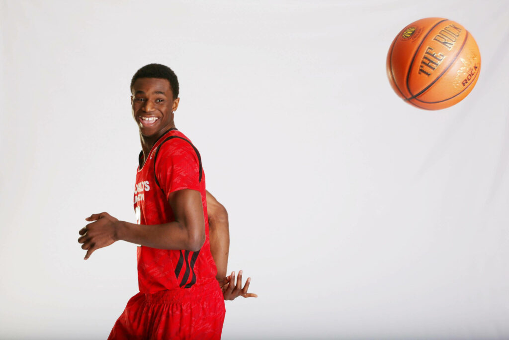 Andrew Wiggins in red jersey smiling and playfully throwing basketball on white background wallpaper