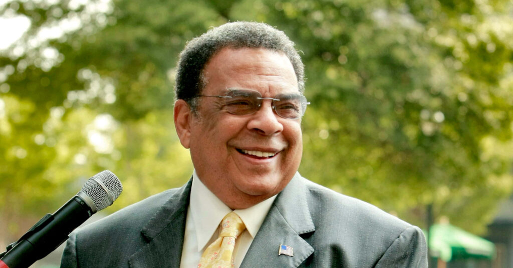 Andrew Young smiling wearing glasses and suit with green tree-filled vibrant outdoor background Wallpaper