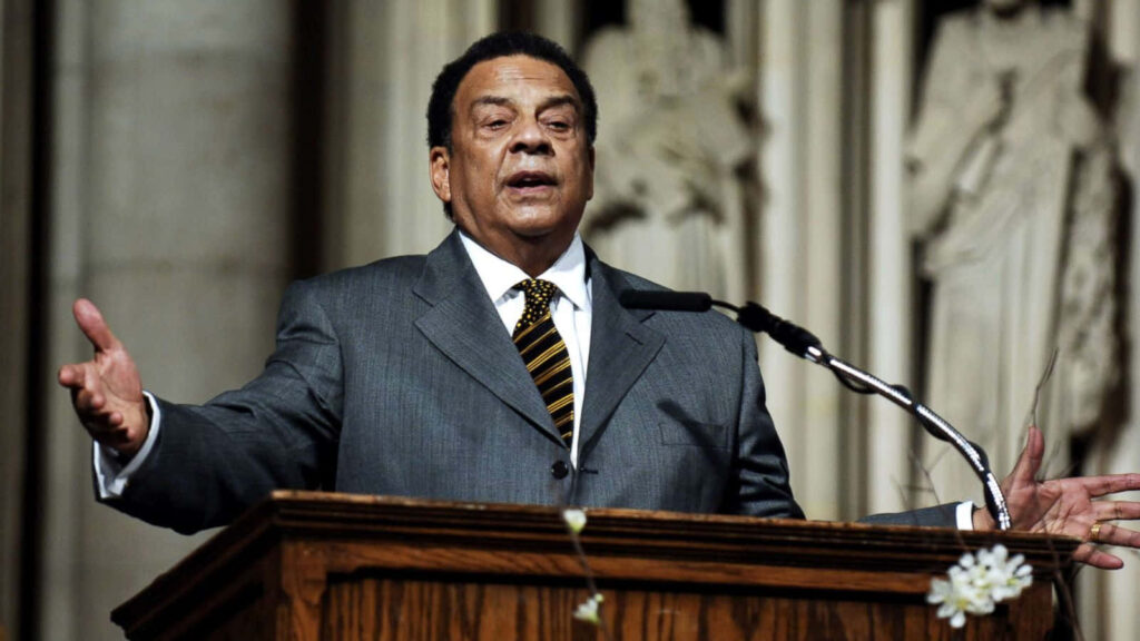 Andrew Young speaking passionately at church podium with grand architectural columns background Wallpaper