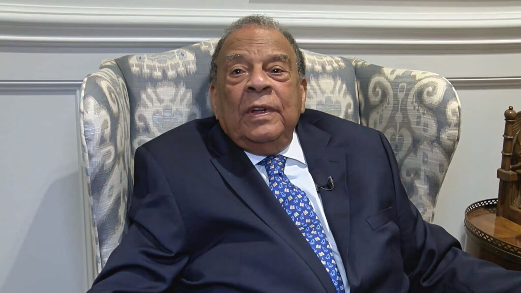 Andrew Young thoughtful interview portrait seated in elegant chair with wallpaper background