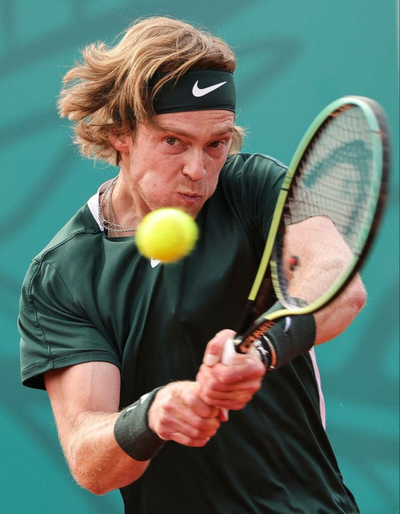 Andrey Rublev powerful backhand tennis shot intense match focus athleticism green court wallpaper