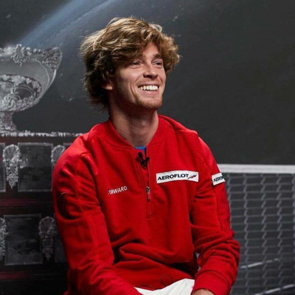 Andrey Rublev focused smiling in red sweatshirt with tennis trophy and net sports wallpaper background