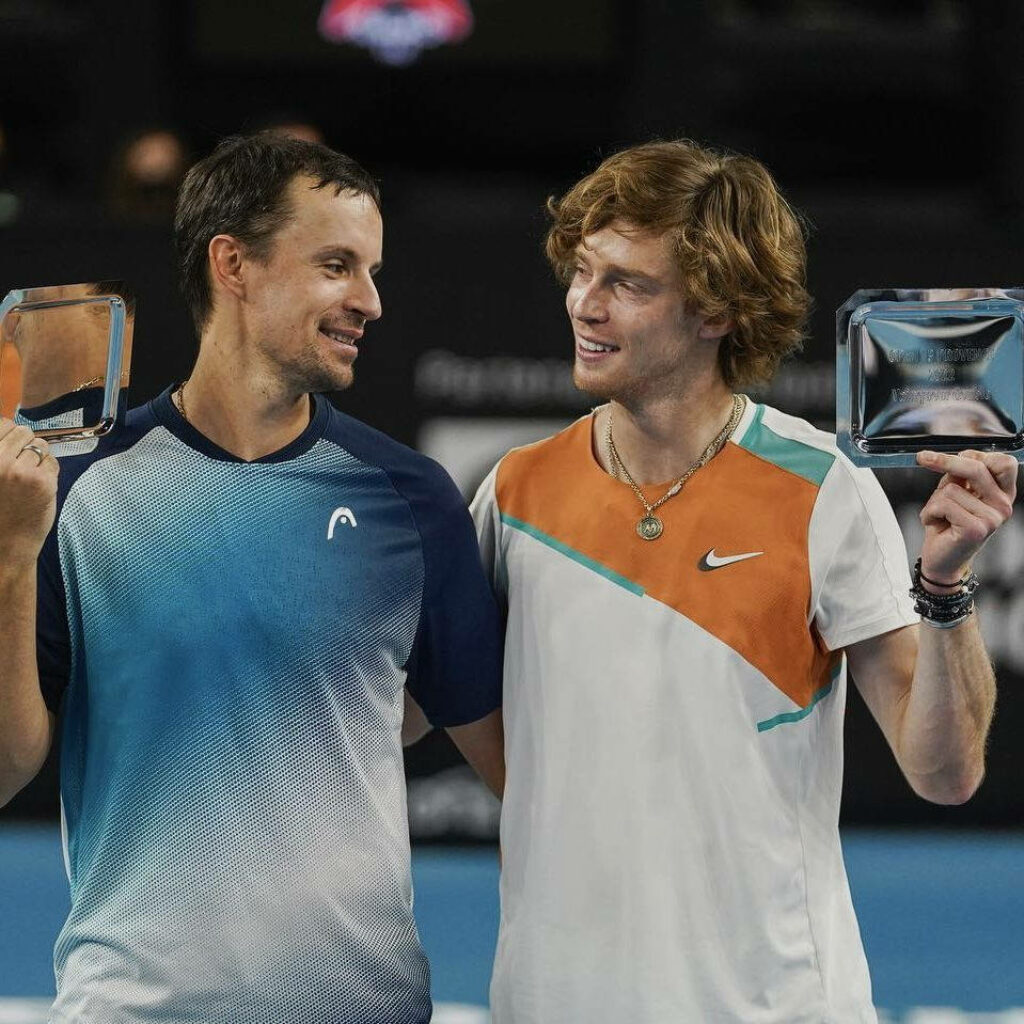 Andrey Rublev and fellow tennis player smiling and celebrating trophy victory on court wallpaper
