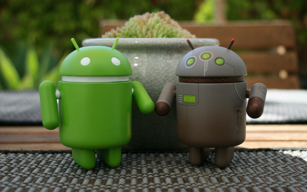 Aesthetic Android Duo: Green and Grey Robots Standing Proudly Next to Potted Plant on Patterned Surface Wallpaper