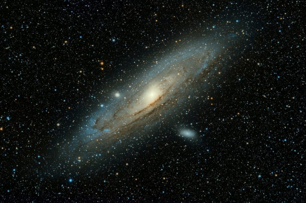 Andromeda Galaxy wallpaper showing golden core and starry blue spiral arms in deep space view