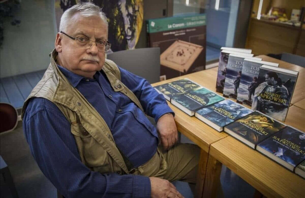 Andrzej Sapkowski at book signing surrounded by his fantasy novels engaging fans wallpaper background