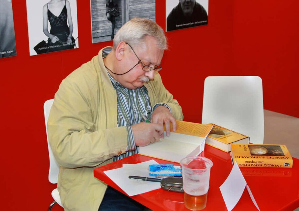 Andrzej Sapkowski signing books at red table author Polish fantasy writer wallpaper background