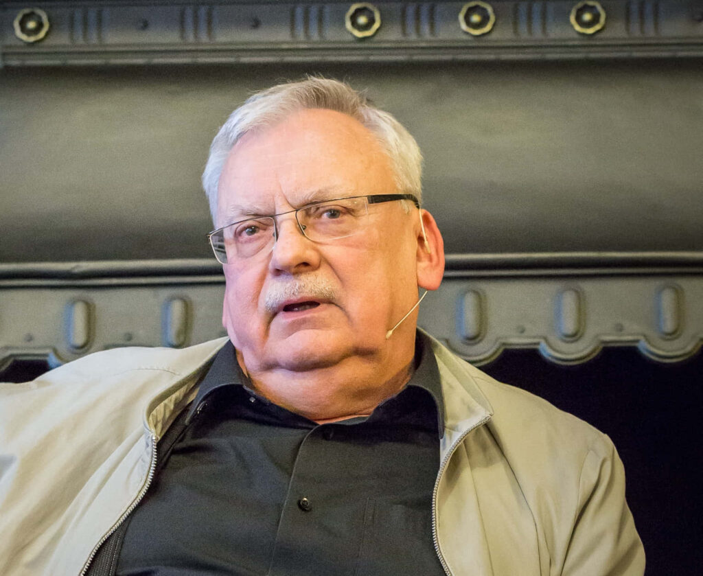 Andrzej Sapkowski speaking event portrait with microphone ornate backdrop wallpaper background