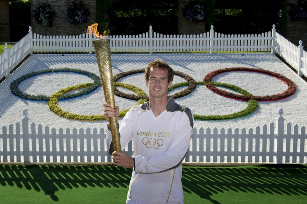 Andy Murray holding Olympic torch at London 2012 relay with Olympic rings background wallpaper