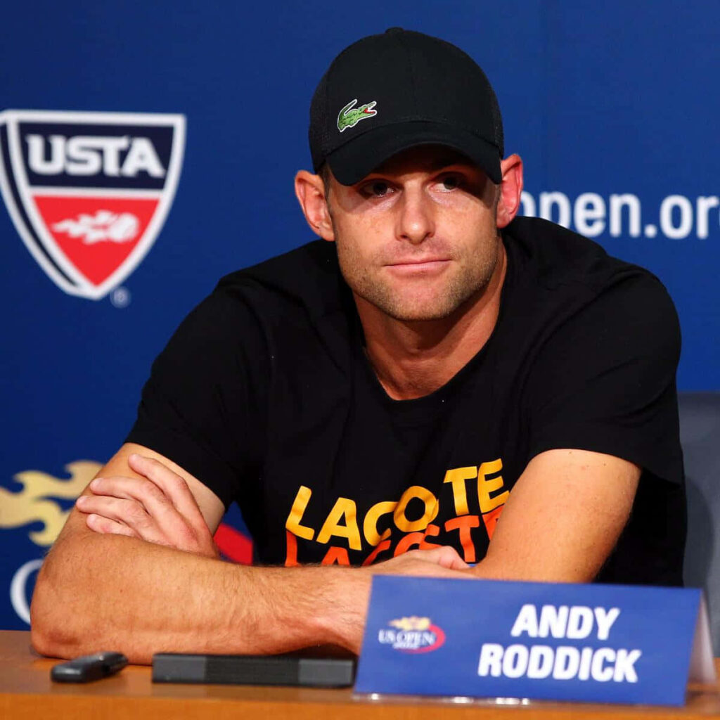 Andy Roddick at US Open press conference wearing black Lacoste shirt and cap with logos Wallpaper