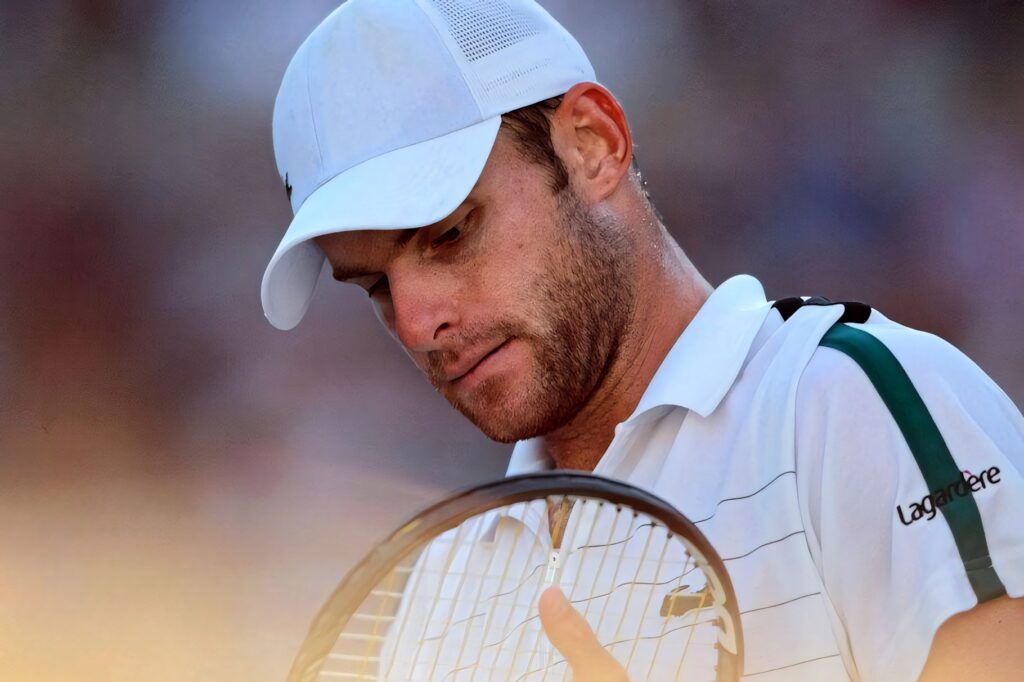 Andy Roddick intensely inspecting tennis racket during match showing focus and determination Wallpaper