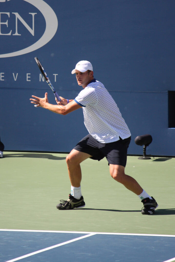 Andy Roddick poised to hit a powerful tennis shot in athletic stance on court wallpaper background