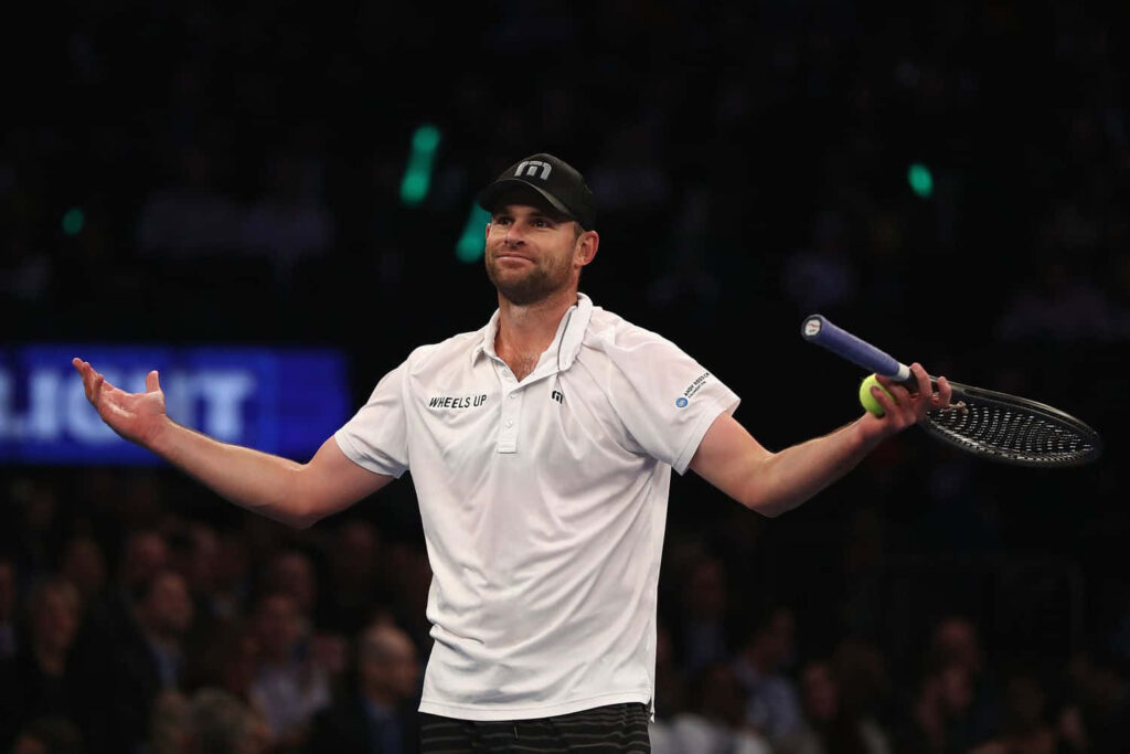 Andy Roddick on tennis court holding racket with arms stretched out during intense match moment Wallpaper