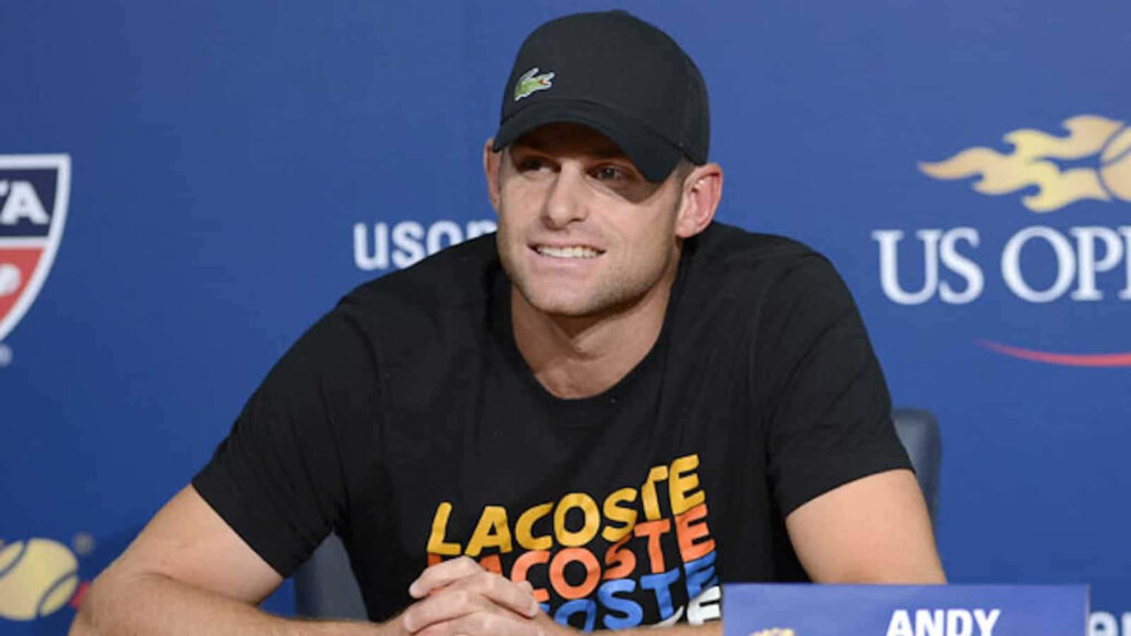 Andy Roddick smiling at US Open press conference wearing black Lacoste shirt and cap Wallpaper