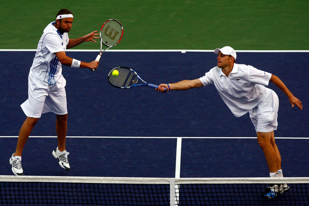 Andy Roddick and Mardy Fish focused in action stretching to return shot during tennis doubles match Wallpaper