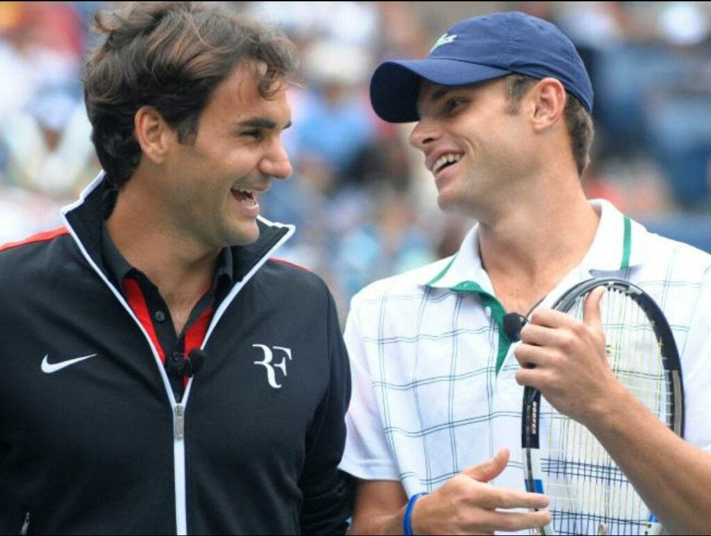 Andy Roddick and Roger Federer smiling on tennis court showing sportsmanship and camaraderie Wallpaper