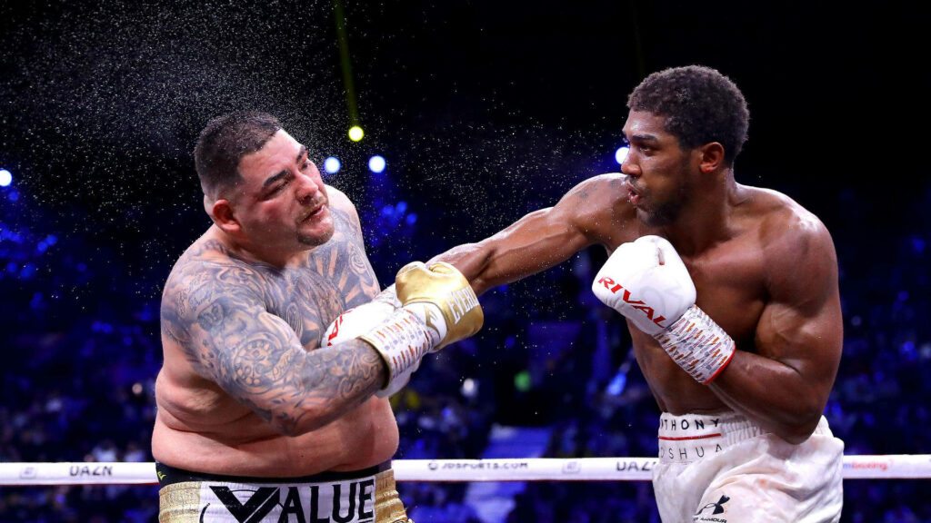 Andy Ruiz Jr. receives a powerful punch in intense boxing match sweat flying inside the ring wallpaper