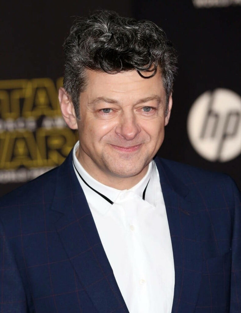 Andy Serkis on Star Wars red carpet in sharp suit with blurred Star Wars logo background wallpaper
