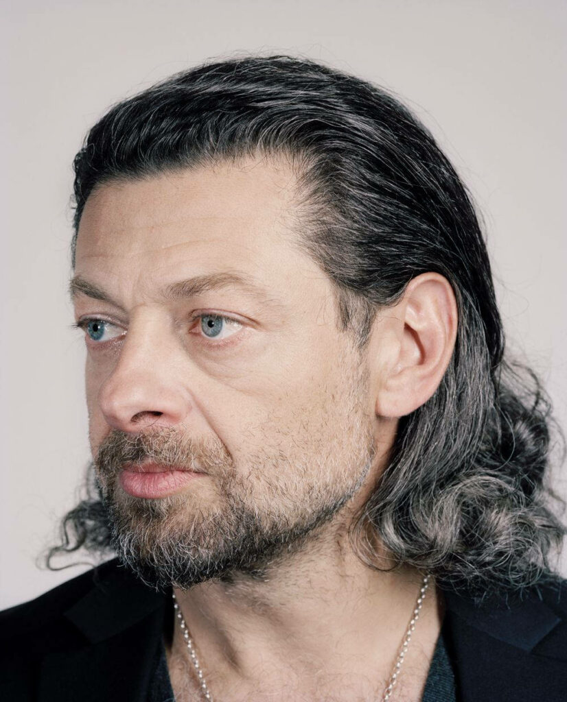 Andy Serkis with long wavy hair thoughtful expression rugged natural look plain background wallpaper
