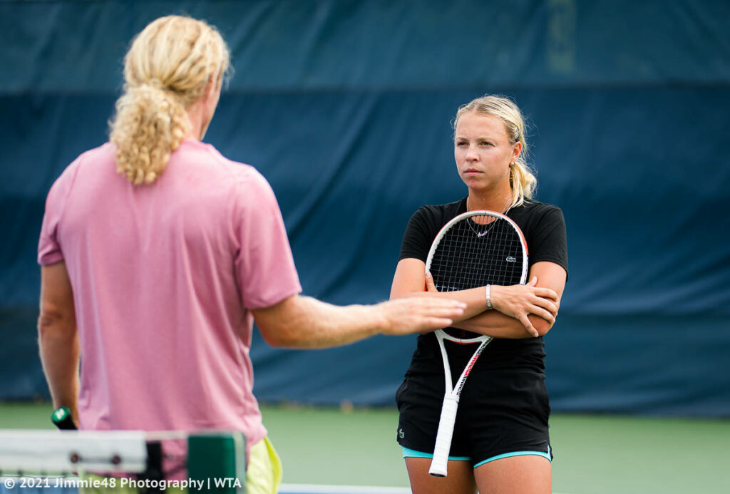 Anett Kontaveit on tennis court arms crossed attentively listening during training session wallpaper