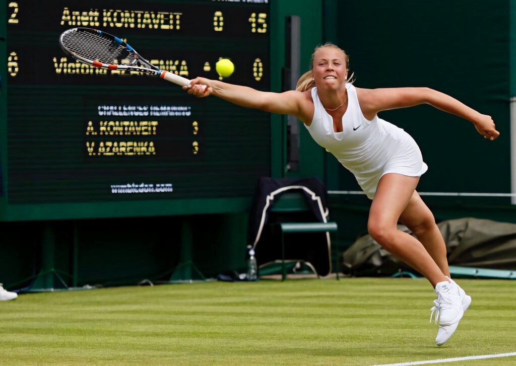 Anett Kontaveit reaching for a tennis ball on grass court during intense athletic match wallpaper