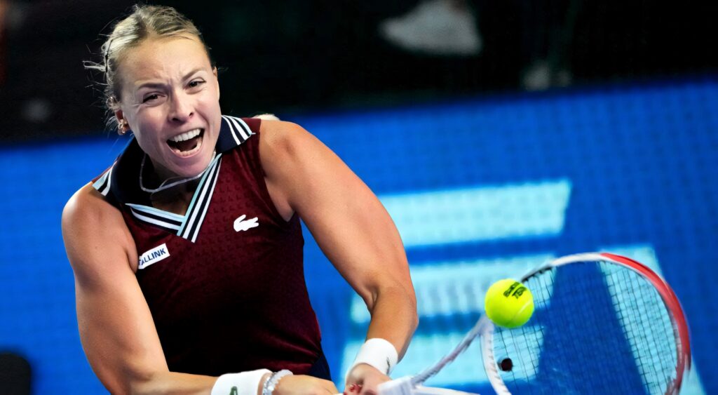Anett Kontaveit hitting powerful backhand shot focused and flexing muscles tennis match Wallpaper