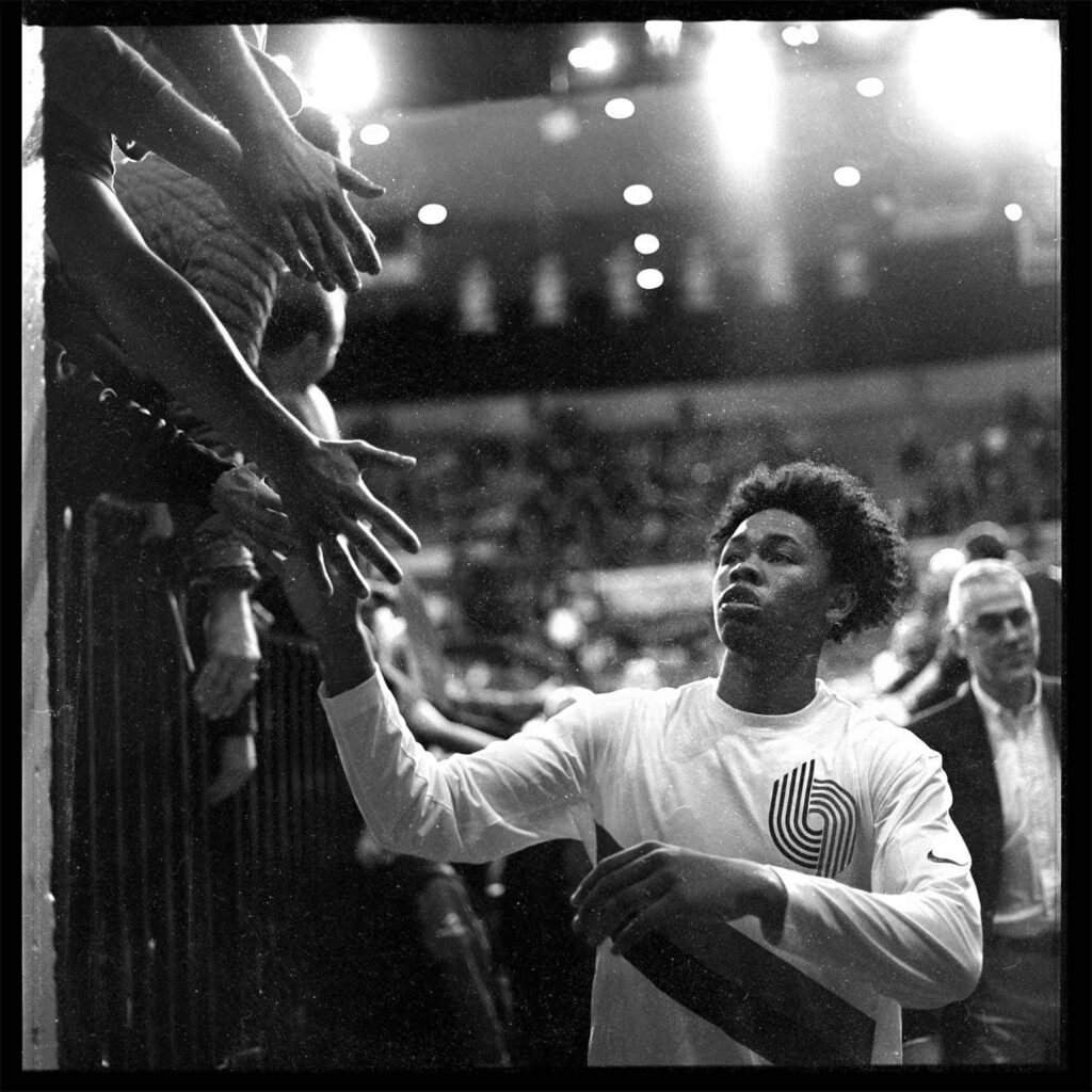 Anfernee Simons courtside high fiving fans after basketball game capturing player fan connection Wallpaper