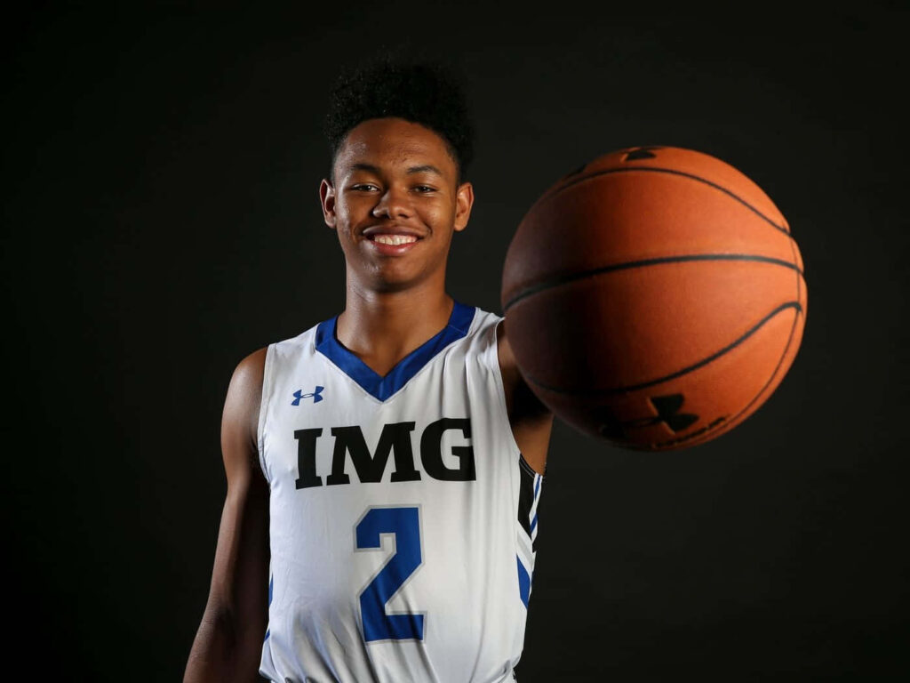 Anfernee Simons in IMG Academy basketball uniform holding basketball with dark background wallpaper