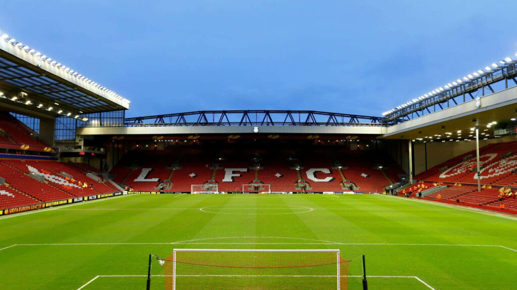 Empty Anfield Stadium at dusk with green pitch and iconic red stands Liverpool FC wallpaper