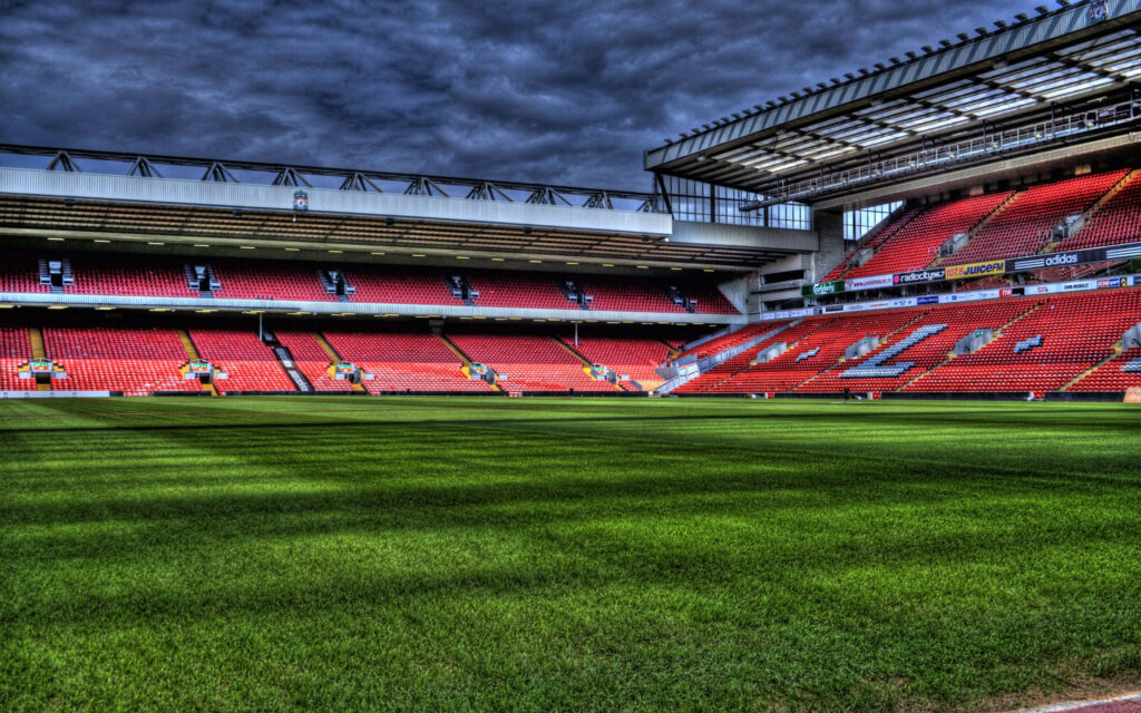 Anfield Stadium interior with red seats and green pitch under dramatic sky Liverpool FC wallpaper