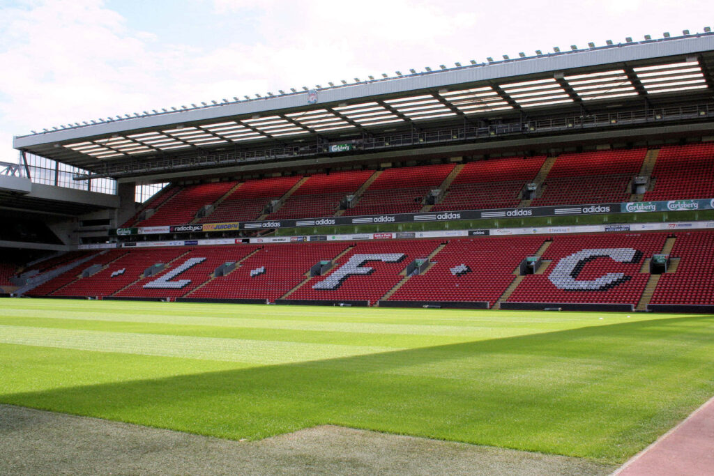 Anfield Stadium interior with vibrant green pitch and iconic red LFC stands wallpaper background