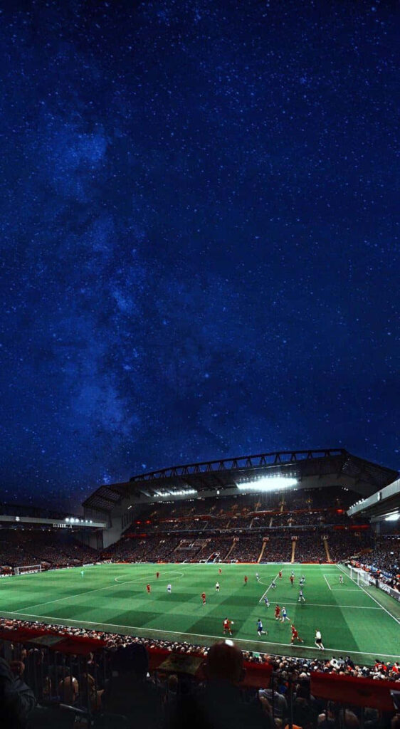 Anfield Stadium lit up during night football match under starry sky vibrant electric atmosphere wallpaper
