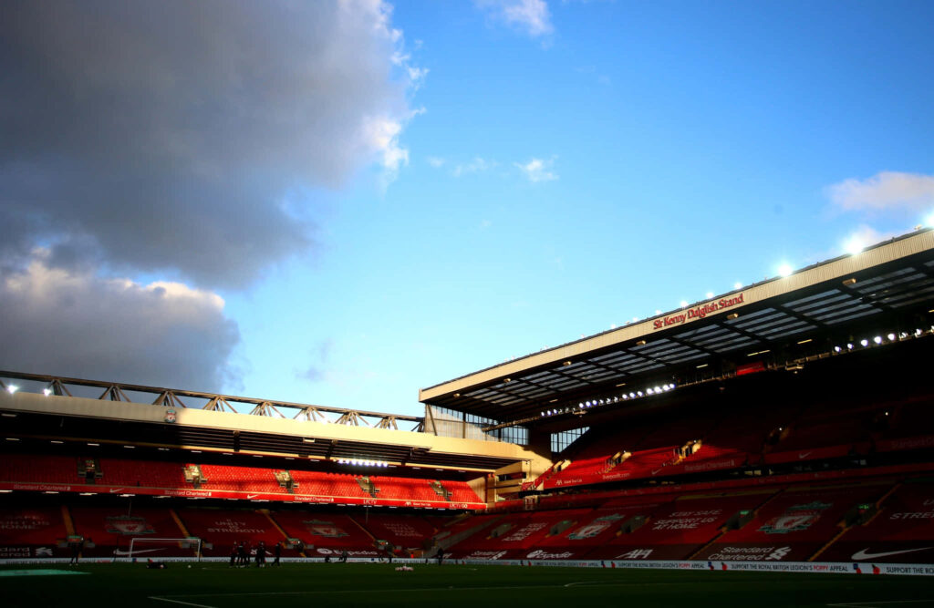 Anfield Stadium sunset glow with iconic red seats and dramatic clouds against blue sky wallpaper