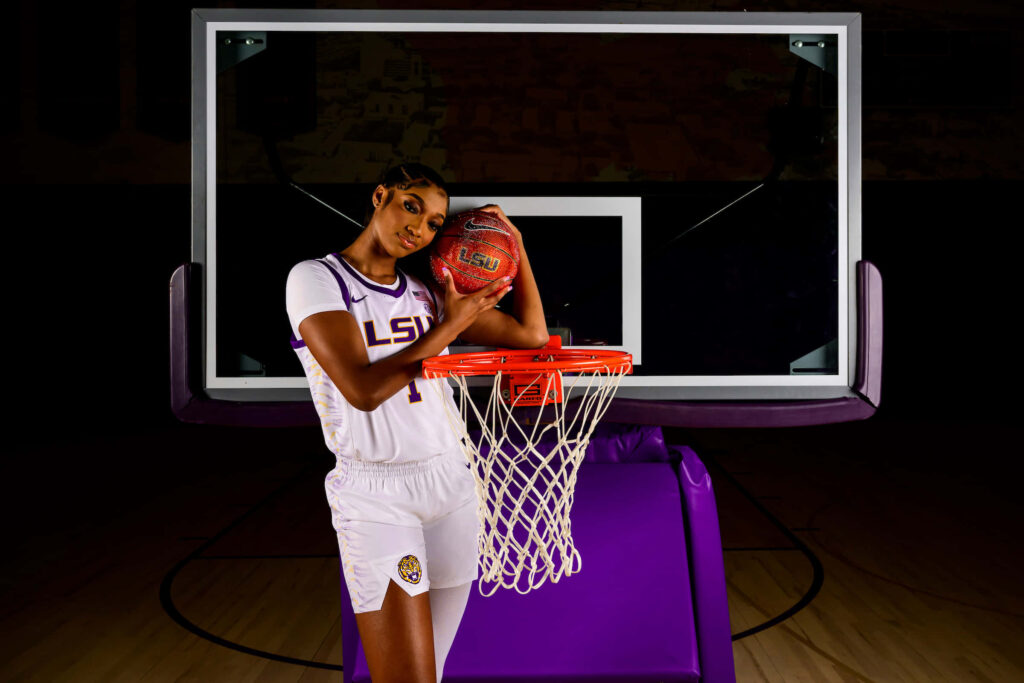 Angel Reese in LSU uniform holding basketball confidently by hoop basketball wallpaper background