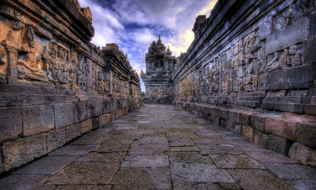 Ancient stone walkway at Angkor Wat temple with carved walls showcasing historic architecture Wallpaper