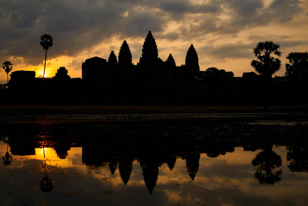 Brown Angkor Wat silhouette wallpaper with sunset sky palm trees and temple reflections