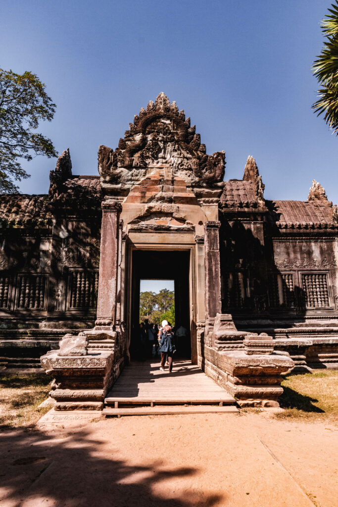 Angkor Wat gateway with intricate stone carvings under clear blue sky ancient Cambodia temple Wallpaper