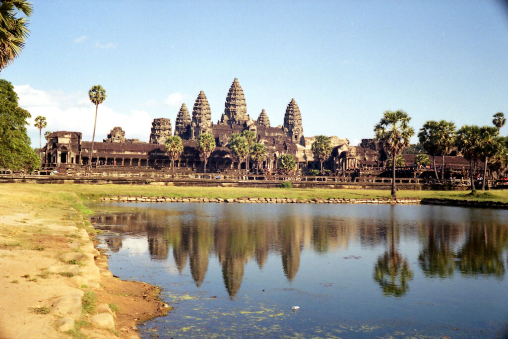 Angkor Wat stone towers reflected in calm water under clear blue sky scenic wallpaper view