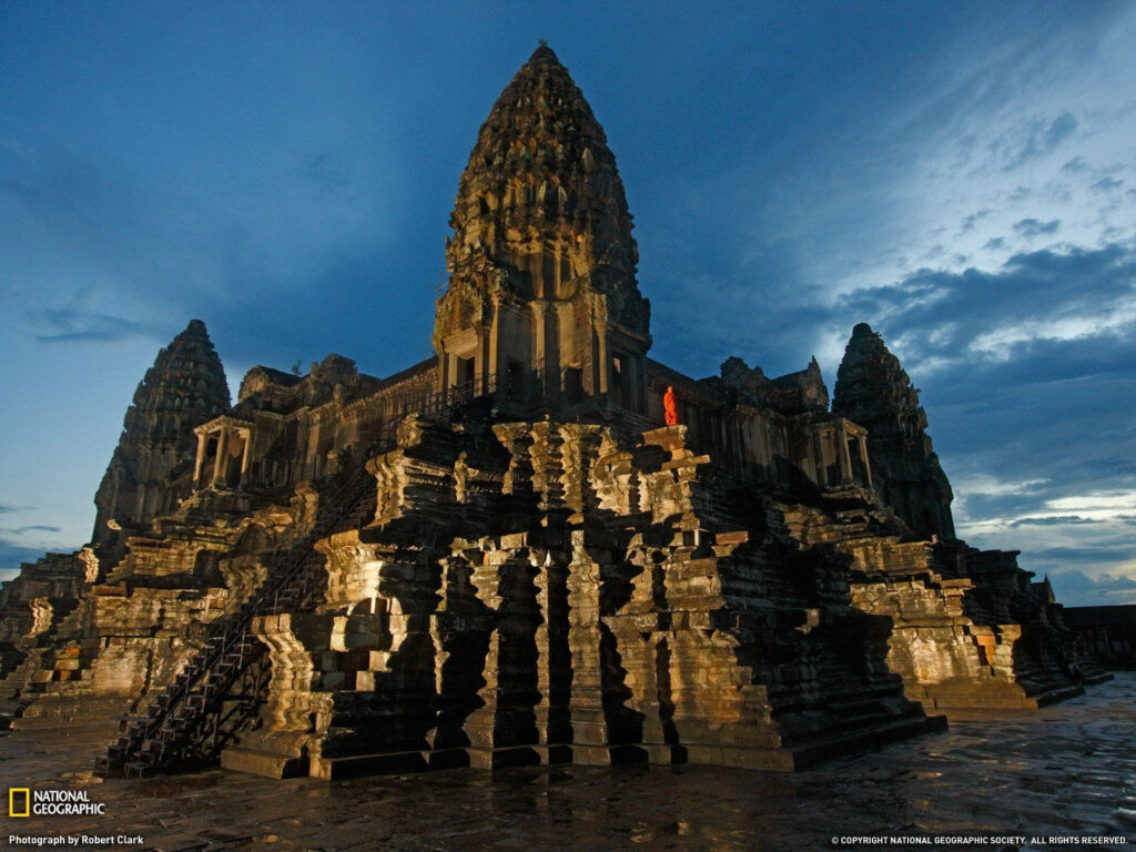 Angkor Wat temple at sunset with ancient stone architecture and vibrant evening sky background Wallpaper
