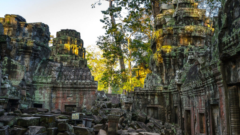 Angkor Wat temple surrounded by lush greenery and sunlight showcasing ancient stone ruins Wallpaper