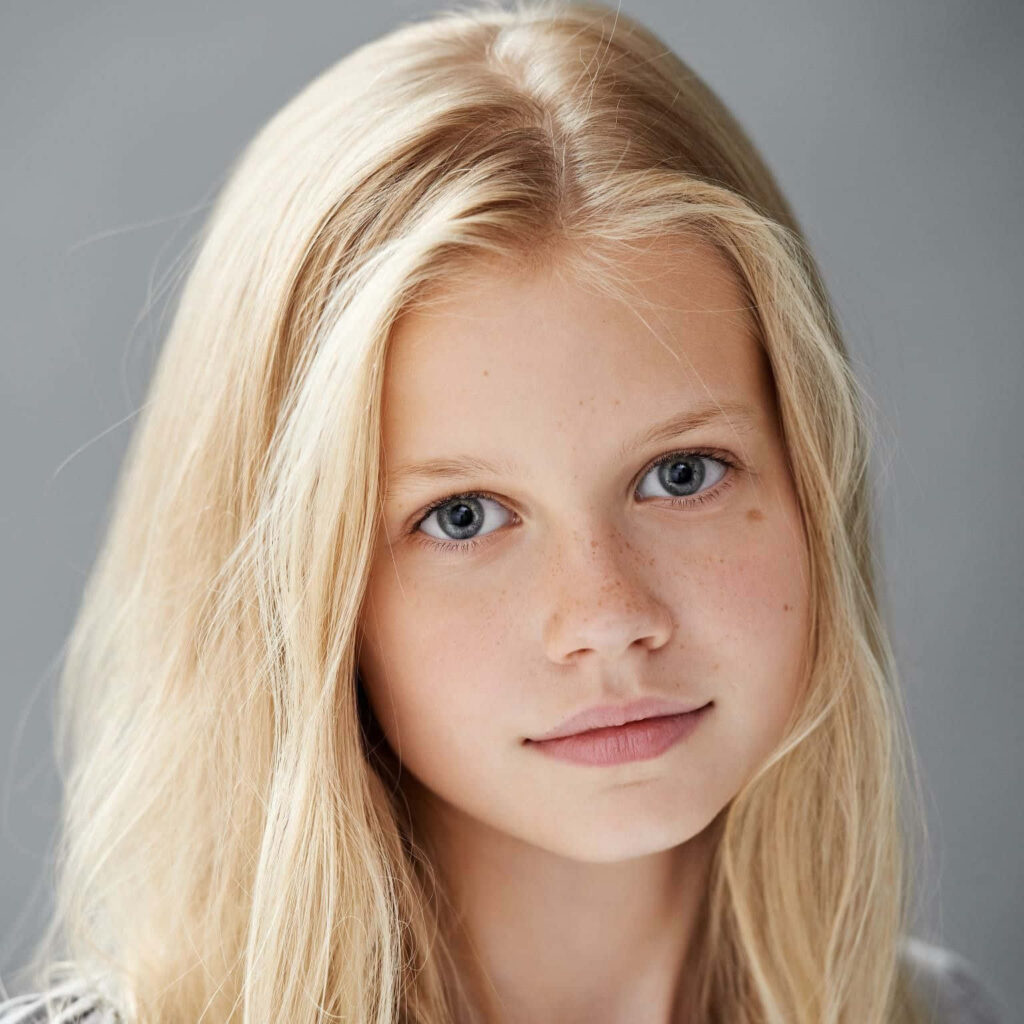 Soft natural portrait of Angourie Rice with blonde hair and youthful glow on gray background Wallpaper
