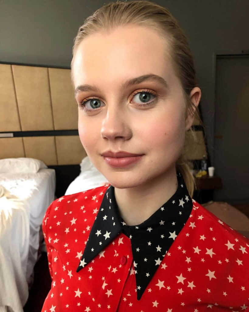 Angourie Rice in red star patterned shirt with black collar stylish vibrant wallpaper background
