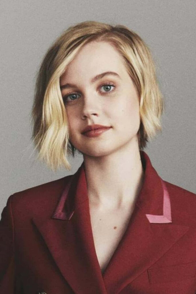 Angourie Rice in stylish red blazer confident pose modern portrait with neutral wallpaper background