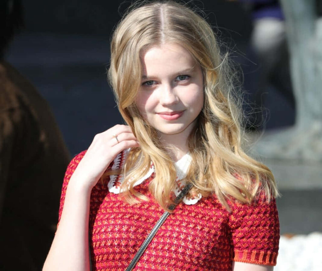 Angourie Rice smiling gently in red patterned dress sunlit portrait bright cheerful wallpaper