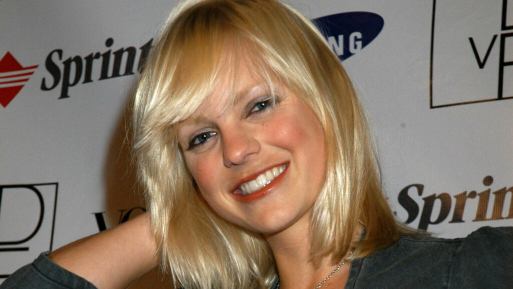 Anna Faris smiling with blonde hair at public event vibrant wallpaper background
