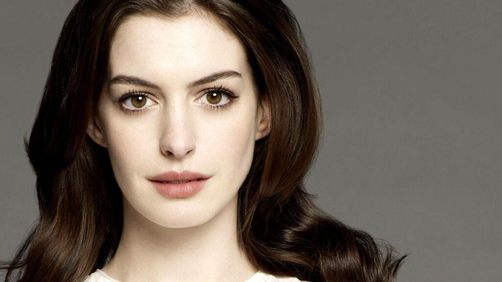 Close-up portrait of Anne Hathaway with soft gray background showcasing elegant features Wallpaper