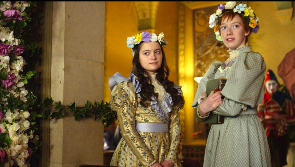 Anne with an E wallpaper Anne and friend with floral crowns in warm golden lit floral room