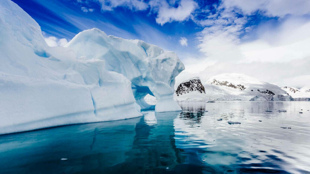 Antarctic glacier reflected in clear blue water under dramatic sky pristine polar landscape wallpaper