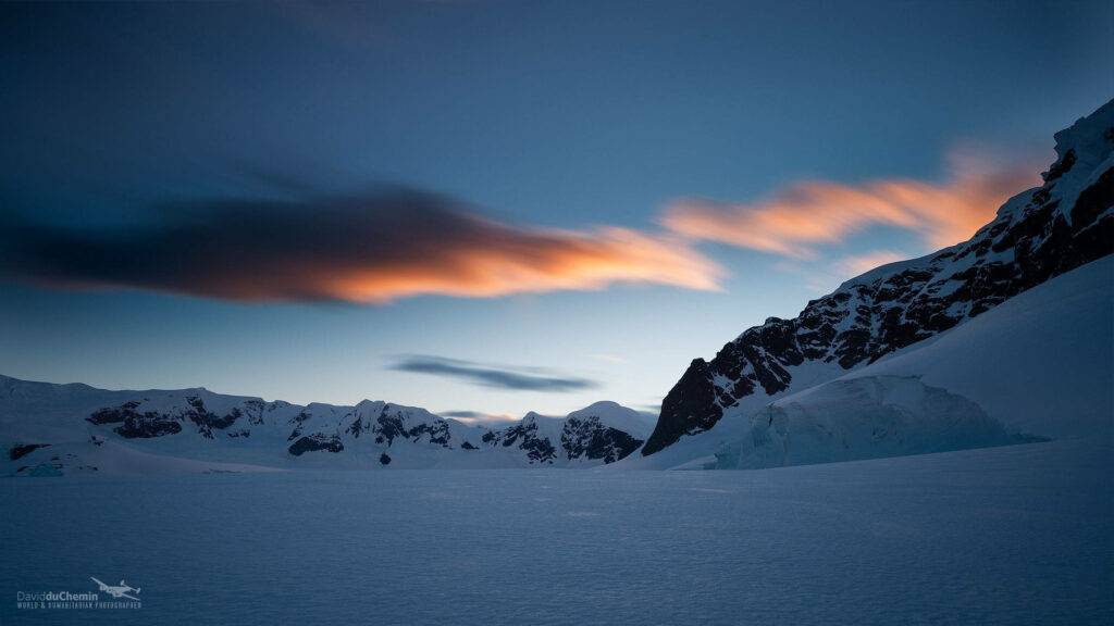 Antarctica landscape with rugged rocks snow-covered peaks and colorful twilight sky wallpaper